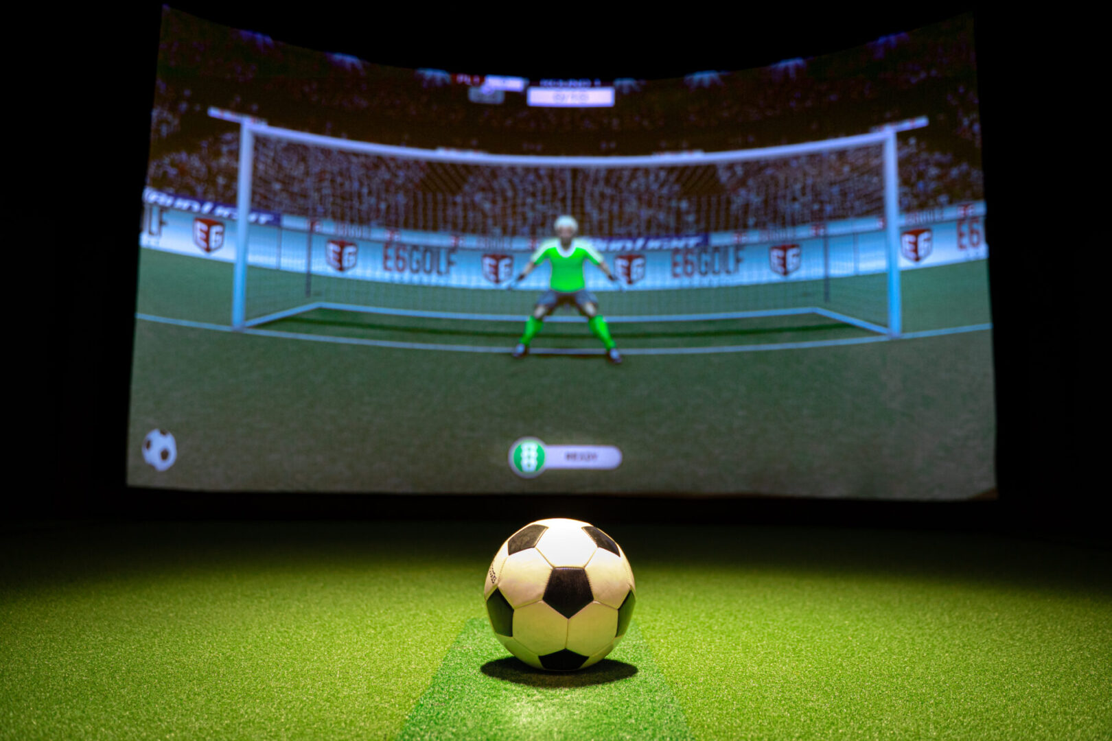 An image of a soccer goal in front of a screen.