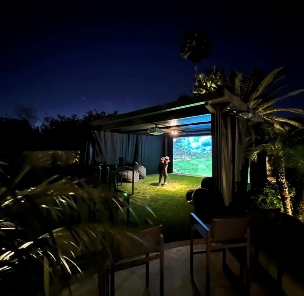 A man is playing a game of outdoor golf at night in a backyard.