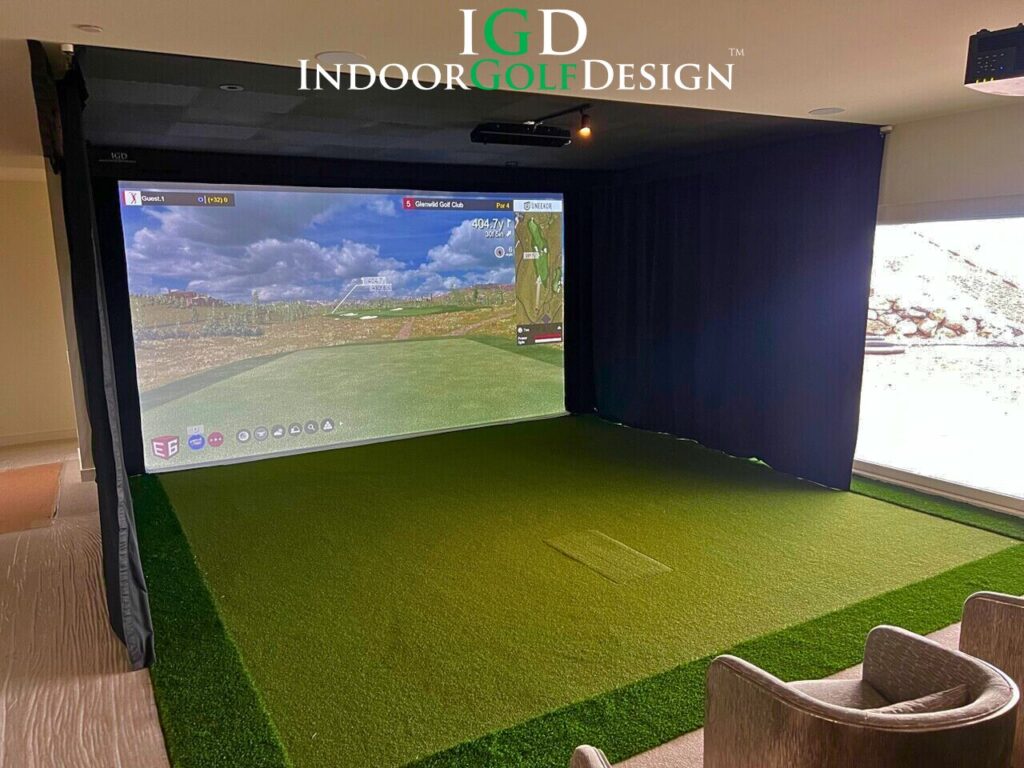 A golf simulator in a room with windows and a screen.