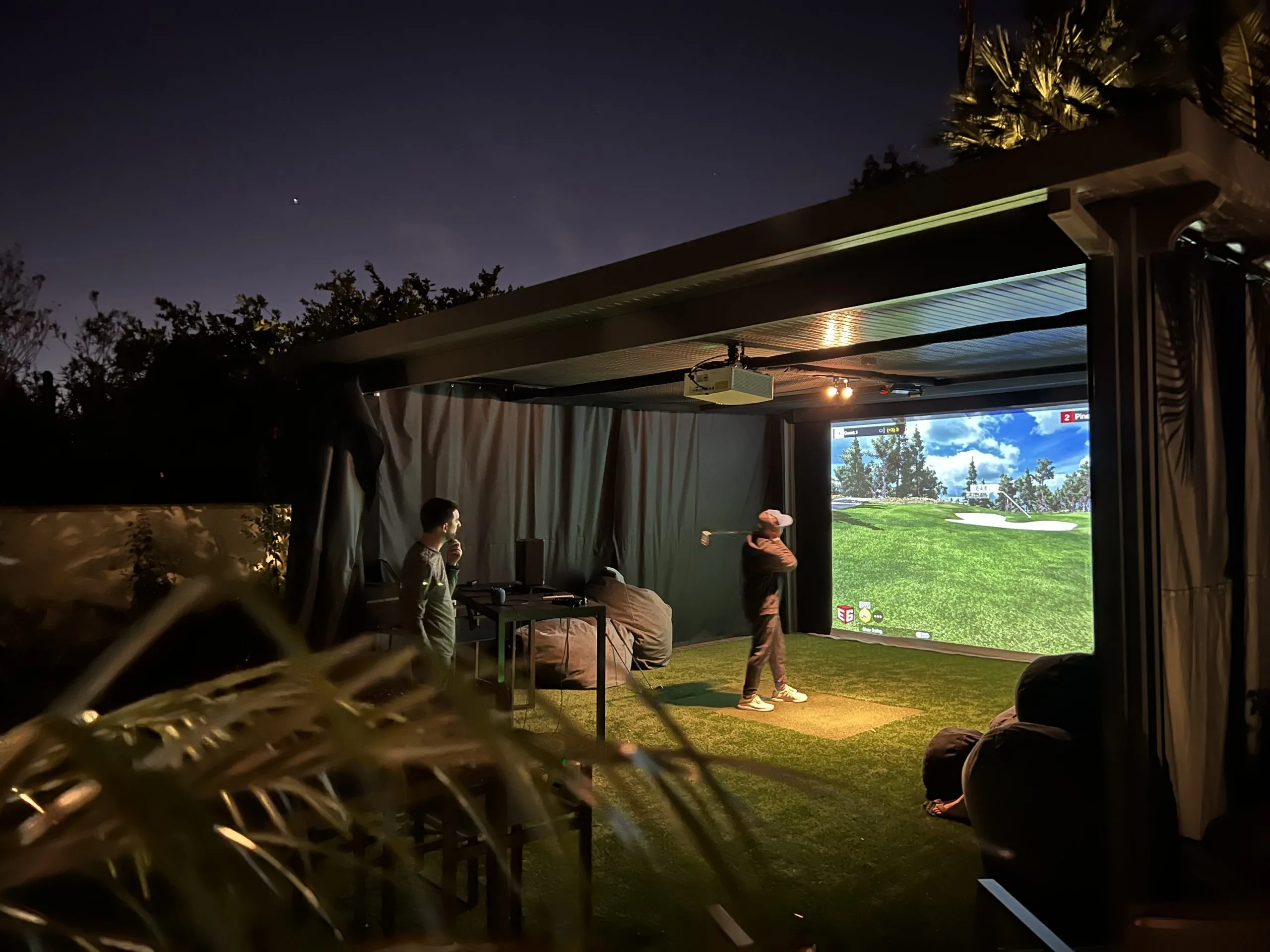 Outdoor covered patio golf simulator installation at night